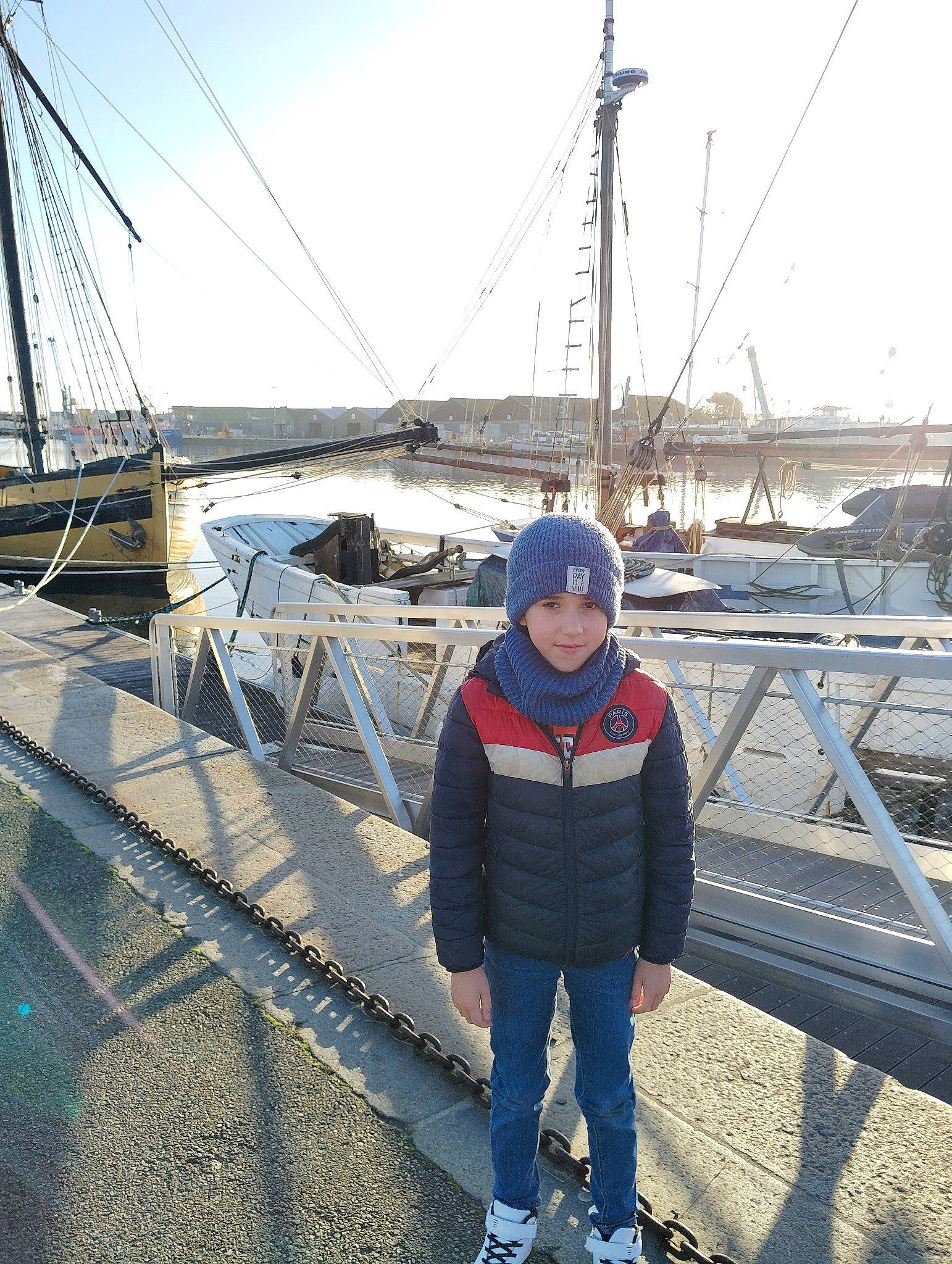 Maël participe au concours pour gagner de l'argent avec cette photo : boat, boats_and_boating_equipment_and_supplies, bridge, dock, fence, goggles, harbor, hat, headwear, mast, naval_architecture, nonbuilding_structure, person, sailboat, ship, sky, travel, vehicle, water, water_transportation