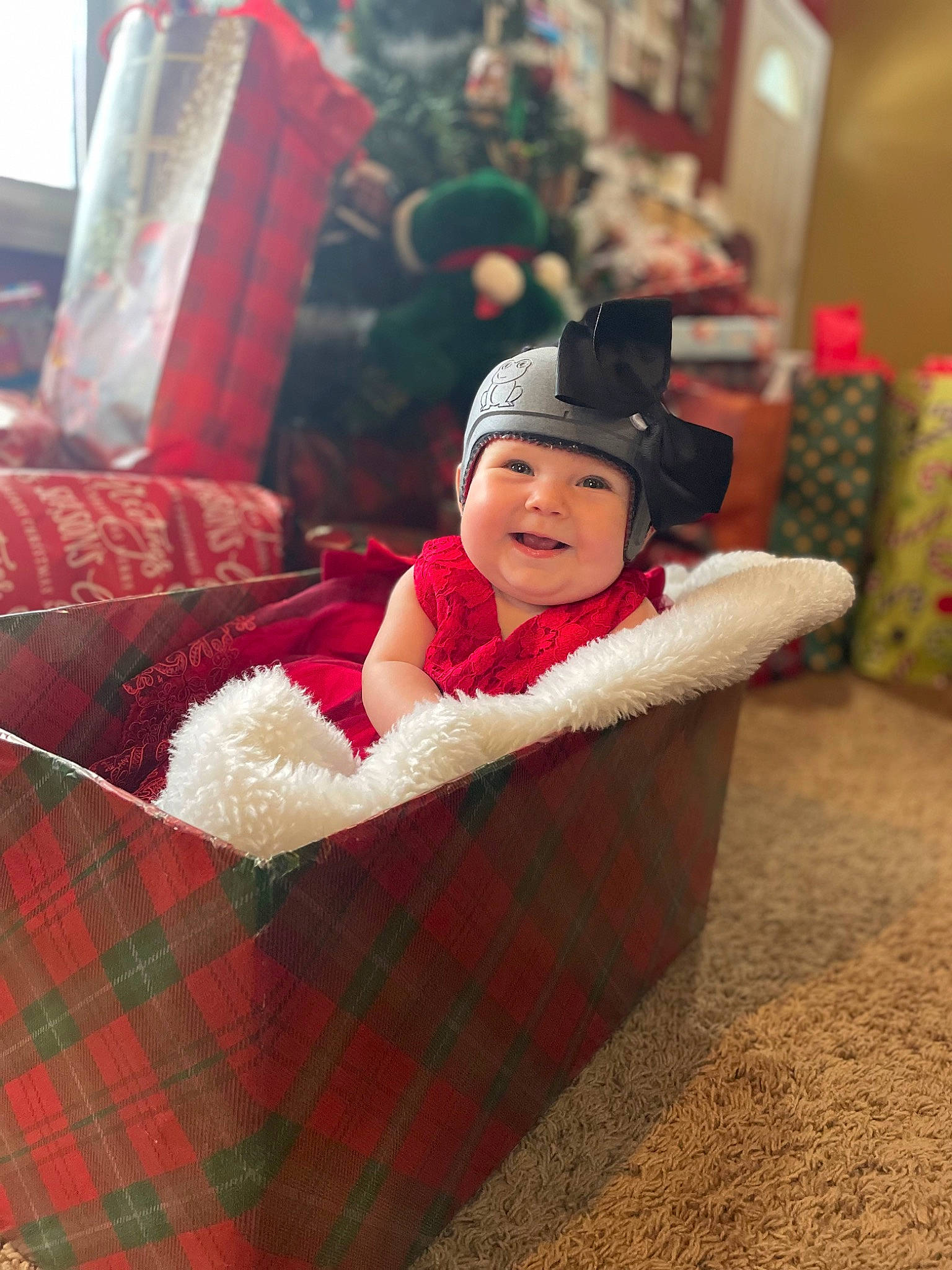 Amelia is registered to the contest to win money with this photo: baby, baby_toddler_clothing, carmine, child, christmas, christmas_eve, comfort, event, fun, grass, happy, headwear, holiday, linens, pattern, person, plaid, room, sitting, tartan