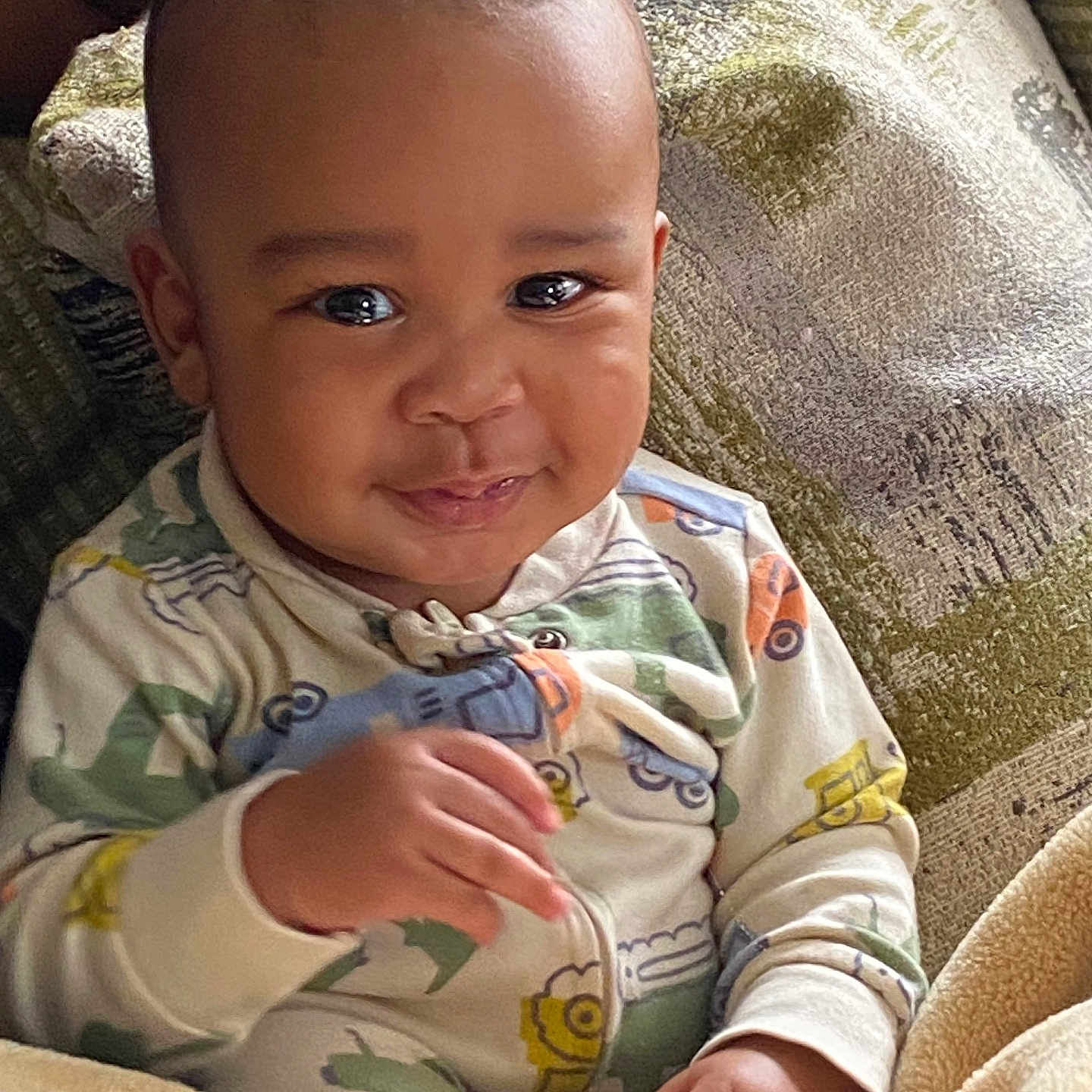 Omari joined the competition — help win amazing prizes! baby, child, smile, face, eyes, hand, onesie, clothing, blanket, couch, fabric, texture, person, infant, indoor, cozy, cute, portrait, young, happy