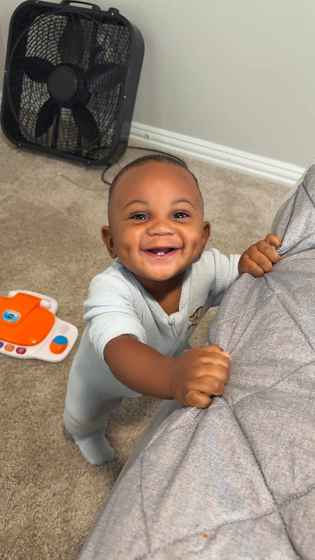 Toriyan joined the competition — help win amazing prizes! baby, smiling, dimples, carpet, toy, fan, bedspread, hand, infant, child, indoors, happy, clothing, standing, face, cute, person, home, play, fingers