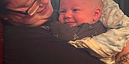 John is registered to the contest to win money with this photo: accessories, baby, clothing, earring, face, furniture, glasses, happy, head, indoors, jewelry, necklace, newborn, person, photography, portrait, skin, smile, t_shirt, tattoo