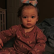 Hazel is registered to the contest to win money with this photo: toddler, child, pajamas, bow, butterfly_pattern, indoor, bedroom, blanket, soft_lighting, face, hands, seated, expression, cozy, home, person, young_child, cute, portrait, clothing