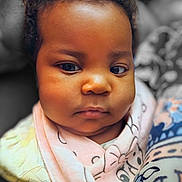 Railey is registered to the contest to win money with this photo: baby, child, face, closeup, portrait, infant, bib, clothing, patterned_fabric, cute, young_child, soft_lighting, indoor, person, head, expression, serious, skin, eyes, hair