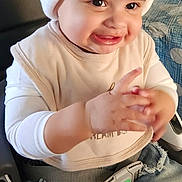 Malia is registered to the contest to win money with this photo: baby, bib, car_seat, child, clapping, clothing, cute, face, hands, happy, hat, indoor, jeans, person, pom_pom, ripped_jeans, seatbelt, seated, smiling, young_child