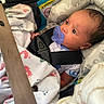 baby, infant, car_seat, pacifier, blanket, elephant_pattern, safety_buckle, clothing, face, child, seatbelt, cute, newborn, indoors, expression, holding, soft_toy, portrait, baby_girl, baby_boy