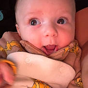 Tiago a rejoint le concours — aidez-le/la à gagner de superbes lots ! baby, infant, face, eyes, mouth_open, smile, onesie, simba, cartoon_print, clothing, close_up, portrait, hand, fingers, skin, person, cute, indoor, held, blanket