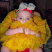 Azareé is registered to the contest to win money with this photo: baby, child, blue_eyes, headband, bow, yellow_fabric, clothing, hands, legs, indoor, person, cute, infant, sitting, closeup, portrait, face, expression, soft_texture, fabric