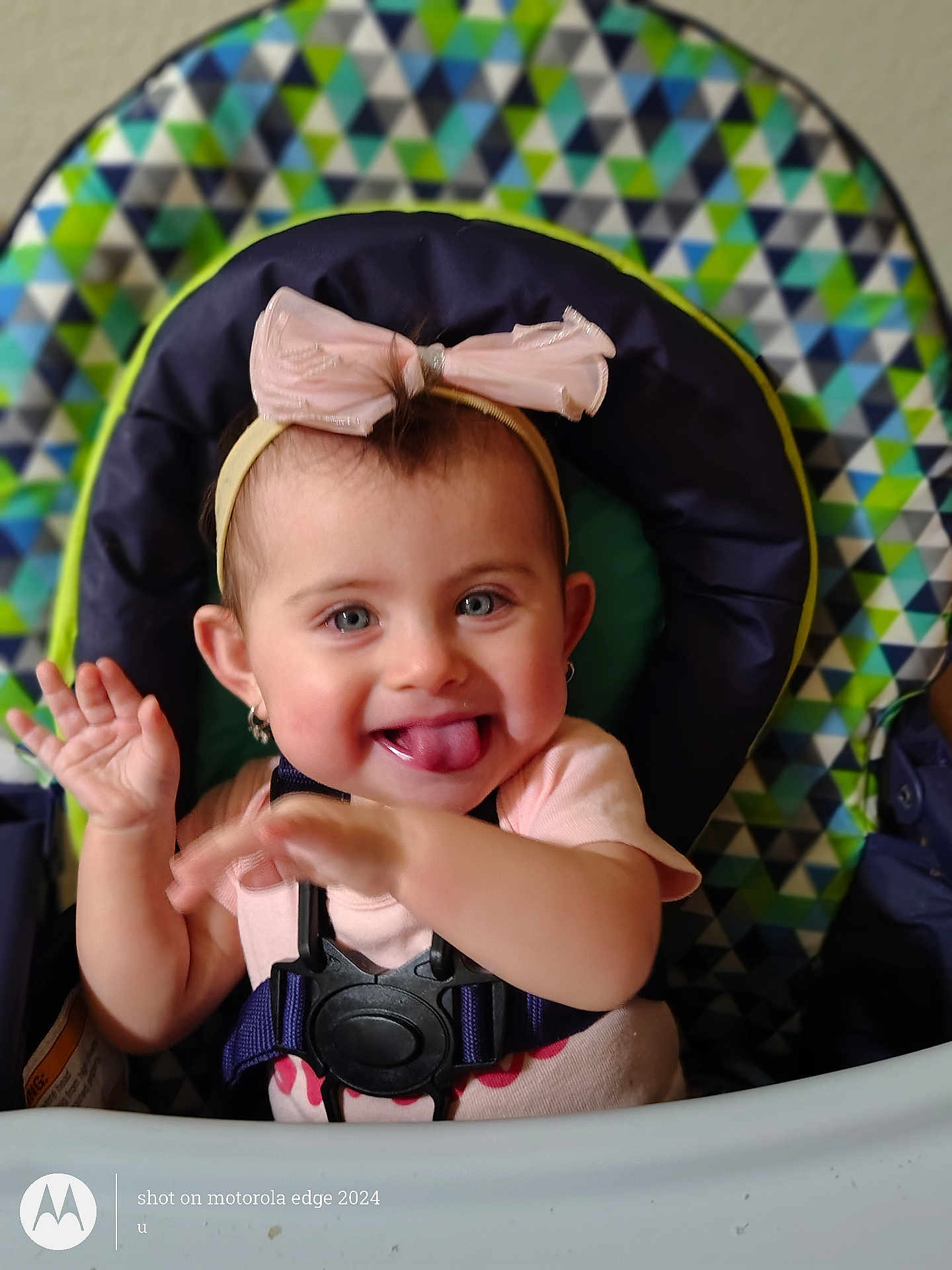 Azareé joined the competition — help win amazing prizes! baby, baby_seat, blue_eyes, bow, cheerful, child, cute, happy, headband, high_chair, indoor, infant, patterned_background, person, pink_shirt, playful, sitting, smiling, tongue_out, waving_hands