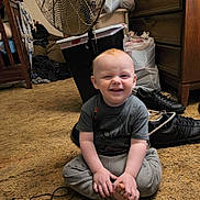 Hardin is registered to the contest to win money with this photo: toddler, child, smiling, sitting, carpet, fan, shoes, dresser, clothing, room, floor, cord, toy, hair, hand, foot, indoor, person, furniture, casual