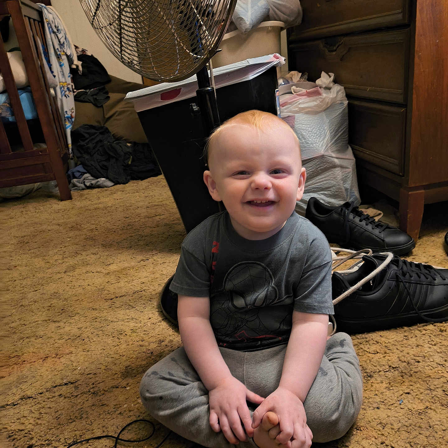 Hardin is registered to the contest to win money with this photo: carpet, casual, child, clothing, cord, dresser, fan, floor, foot, furniture, hair, hand, indoor, person, room, shoes, sitting, smiling, toddler, toy