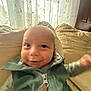 Silas is registered to the contest to win money with this photo: baby, smiling, jacket, couch, pillow, indoor, curtains, window, face, child, person, happy, closeup, home, infant, apparel, seated, expression, cozy, fabric