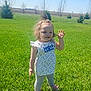 Ellaria is registered to the contest to win money with this photo: toddler, child, grass, outdoor, sunny, smiling, waving, topknot, greenery, nature, daylight, casual_clothing, leggings, shoes, field, trees, blue_sky, happy, person, young_child