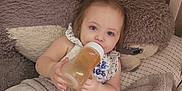 Ellaria joined the competition — help win amazing prizes! baby, bottle, blanket, crib, plush_toy, child, infant, sitting, cozy, soft_texture, bottle_feeding, cute, indoor, person, toy, blanket_wrap, hair_tie, pajamas, sleeping_area, comfort
