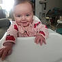 Zoey is registered to the contest to win money with this photo: baby, child, high_chair, pink_clothing, ladybug_pattern, smiling, indoor, living_room, furniture, person, cute, infant, happy, face, hand, table, seat, cozy, home, portrait