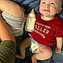 baby, smiling, red_shirt, diaper, bottle, blanket, blue, person, arm, child, lying_down, happy, infant, casual, indoor, cute, relaxed, skin, clothing, human