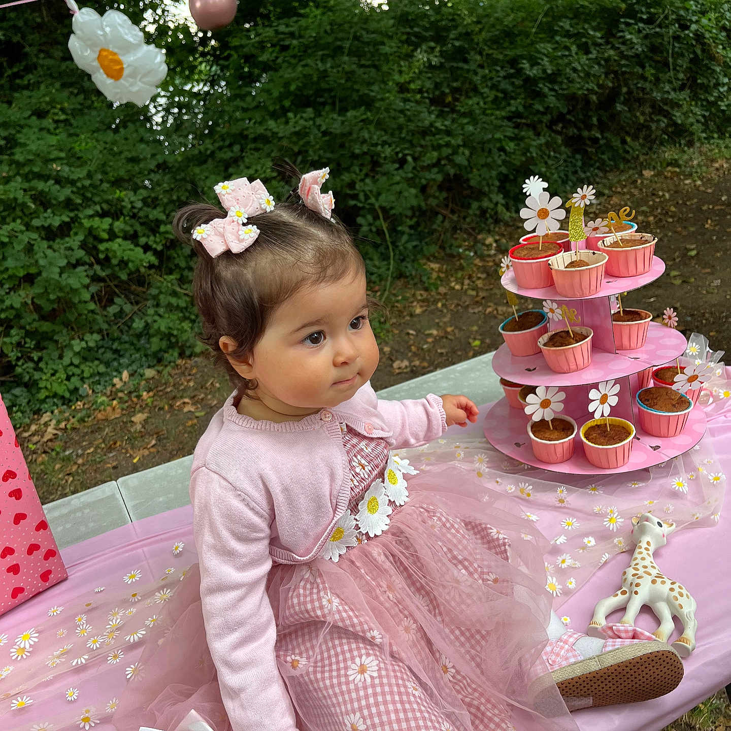 Hilal participe au concours pour gagner de l'argent avec cette photo : birthday_crown, celebration, child, cupcakes, cute, flower_pattern, food, grass, hair_bows, nature, outdoor, party, pink_cardigan, pink_dress, sitting, smile, tablecloth, toddler, toy_giraffe, trees