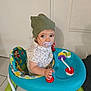 toddler, child, baby_walker, pacifier, green_hat, floral_shirt, indoor, toy, colorful, floor_tiles, seat_cover, jungle_theme, red_handles, white_frame, curious, person, young_child, playful, baby, walker