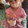 toddler, child, pacifier, plush_toy, pigtails, pink_shirt, striped_shirt, tattoo, balloons, indoor, hand, face, person, toy, purple_pants, cute, baby, holding, sitting, portrait