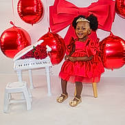 Brihanna Pierre joined the competition — help win amazing prizes! child, girl, red_dress, tiara, balloons, red_balloons, miniature_piano, roses, smiling, sitting, stool, happy, indoor, celebration, dress, gold_shoes, afro_hair, toy, decor, portrait