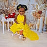 Brihanna Pierre is registered to the contest to win money with this photo: toddler, child, yellow_dress, smiling, afro_hairstyle, bows, golden_shoes, chair, white_piano, red_roses, candles, dried_flowers, studio, portrait, happy, sitting, dress, footwear, background, indoors