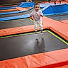 child, toddler, baby, trampoline, indoor, playground, jumping, bouncing, portrait, face, person, pink_shirt, patterned_pants, colorful, recreation, family_activity, sports_facility, padded_floor, play_area, happy
