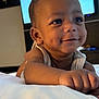 Cayden is registered to the contest to win money with this photo: baby, child, smile, dimples, face, arm, hand, indoor, soft_light, television, blurred_background, lying_down, white_clothing, skin, portrait, closeup, cute, infant, happy, person