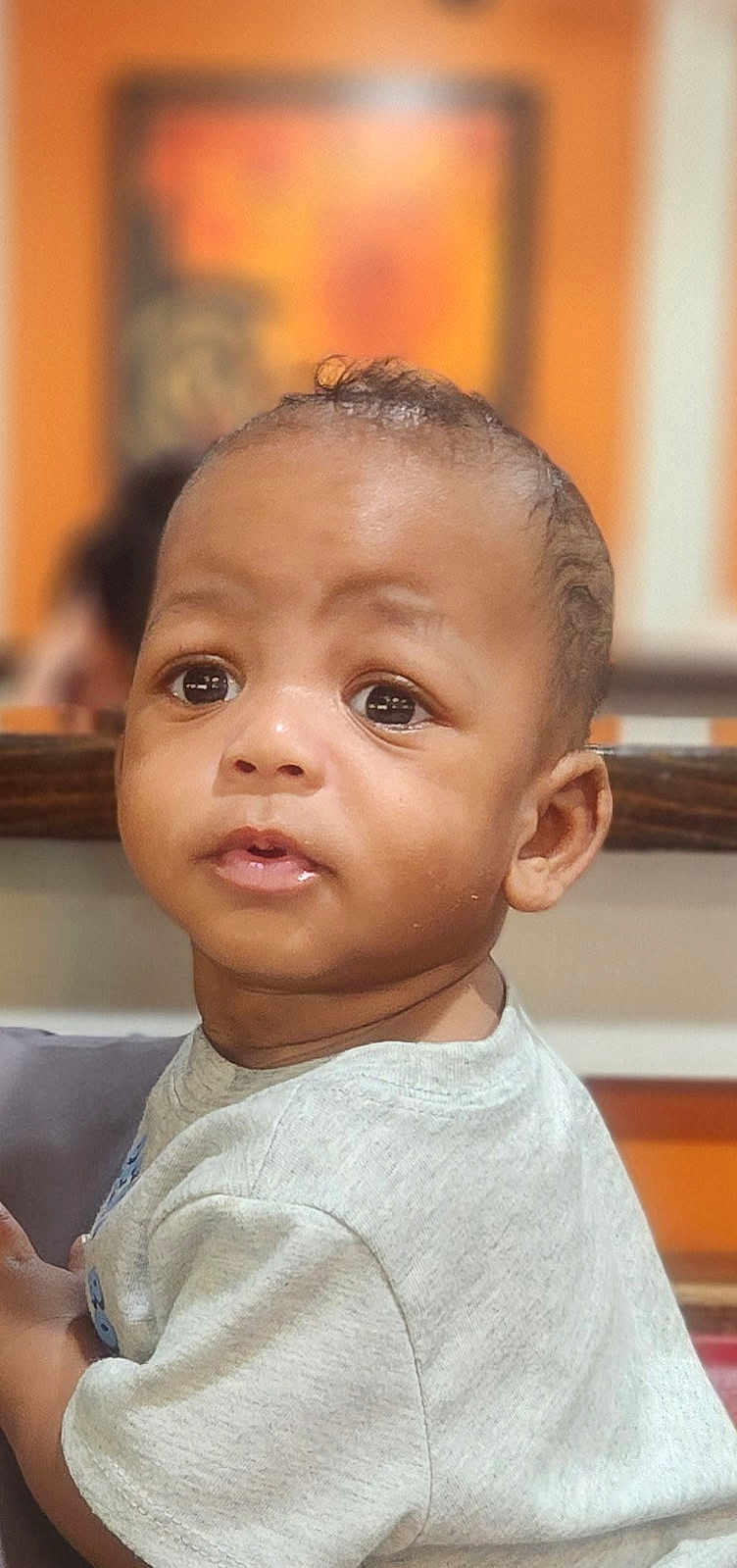 Cayden is registered to the contest to win money with this photo: baby, child, portrait, face, curious, indoor, blurry_background, light_grey_shirt, young_child, closeup, expression, skin, hair, eyes, person, cute, infant, head, looking_away, soft_lighting