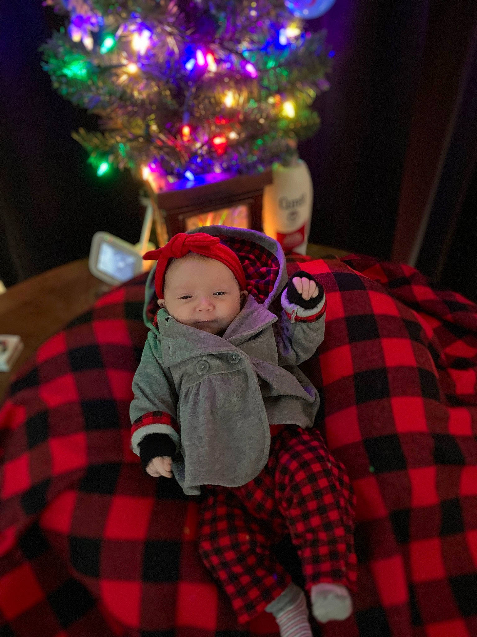 Brynlee is registered to the contest to win money with this photo: baby_toddler_clothing, child, christmas, christmas_decoration, christmas_ornament, christmas_tree, design, event, fun, headwear, holiday, lap, ornament, pattern, person, plaid, plant, purple, sleeve, tartan