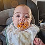 baby, bib, food, messy, high_chair, face, expression, indoor, child, clothing, person, feeding, cute, mess, rainbow_pattern, hand, infant, seat, portrait, home