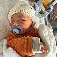 Leyann a rejoint le concours — aidez-le/la à gagner de superbes lots ! baby, bed, blanket, child, cozy, cute, cute_outfit, hand, indoors, infant, knit_hat, newborn, orange_clothing, pacifier, peaceful, person, plush_toy, resting, sleeping, soft_texture