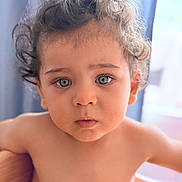 Kaïs a rejoint le concours — aidez-le/la à gagner de superbes lots ! child, toddler, baby, face, blue_eyes, curly_hair, eyes, eyelashes, portrait, close_up, skin, bare_shoulders, expression, indoor, curtain, natural_light, wooden_chair, bokeh, adorable, curious