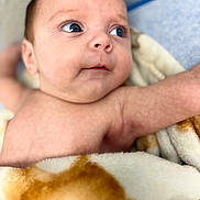 Diego is registered to the contest to win money with this photo: baby, infant, blanket, skin, face, eyes, expression, cute, newborn, child, portrait, soft, warm, cozy, human, closeup, lying_down, indoors, comfort, young