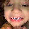 Orion is registered to the contest to win money with this photo: child, close_up, face, smile, orange_clothing, hand, digital_effect, teeth, sparkle, young_child, portrait, indoors, blurry, cute, happy, person, grillz, expression, head, skin