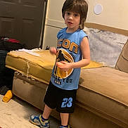 Orion is registered to the contest to win money with this photo: child, indoor, couch, yellow_cushion, blue_shirt, black_shorts, sneakers, floor, door, wall, person, furniture, standing, motion_blur, casual_clothing, short_hair, home, living_room, curious, young