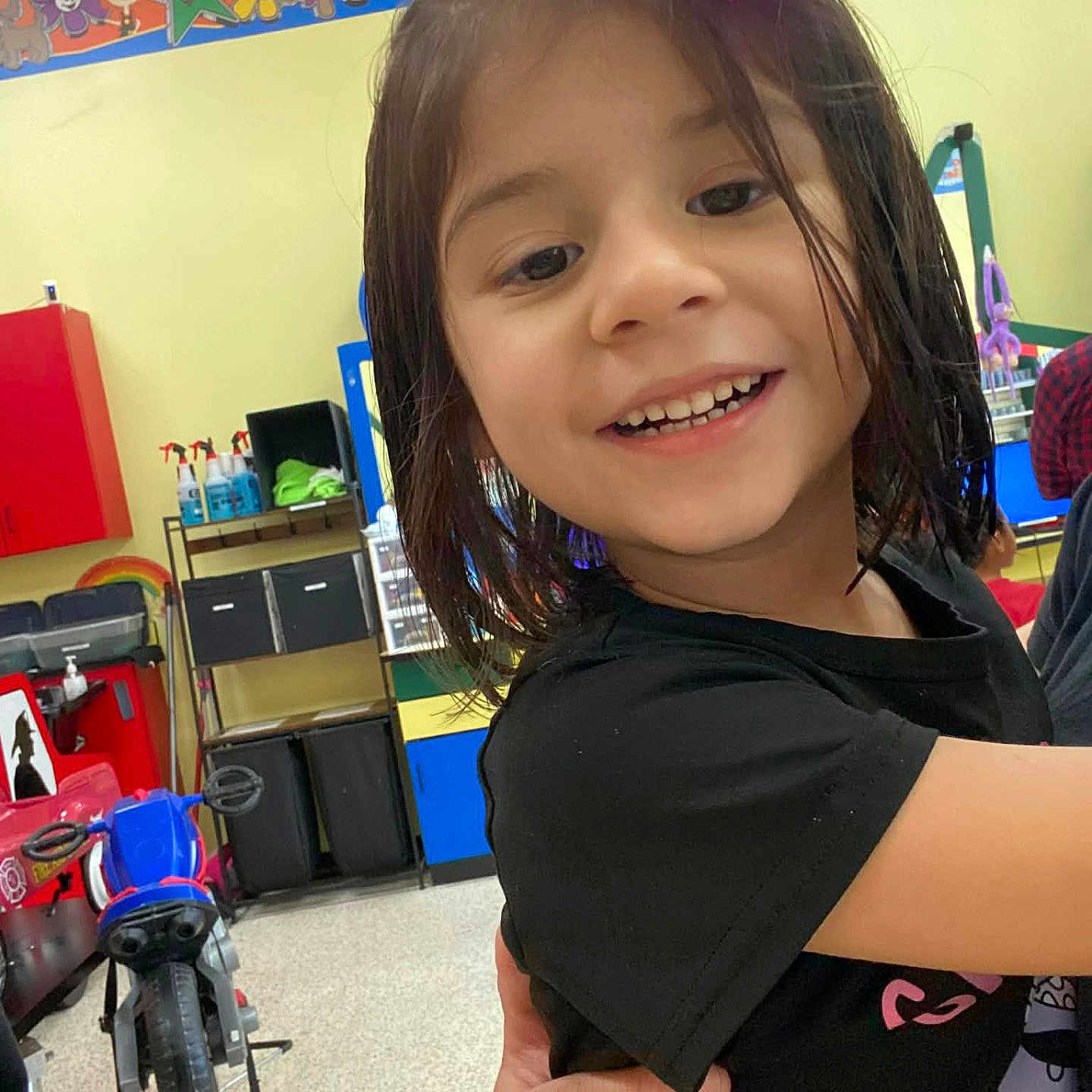 Aryah joined the competition — help win amazing prizes! black_shirt, bow, child, classroom, colorful, cute, decorations, education, furniture, girl, hair, hand, happy, indoor, person, play, portrait, smiling, toys, young