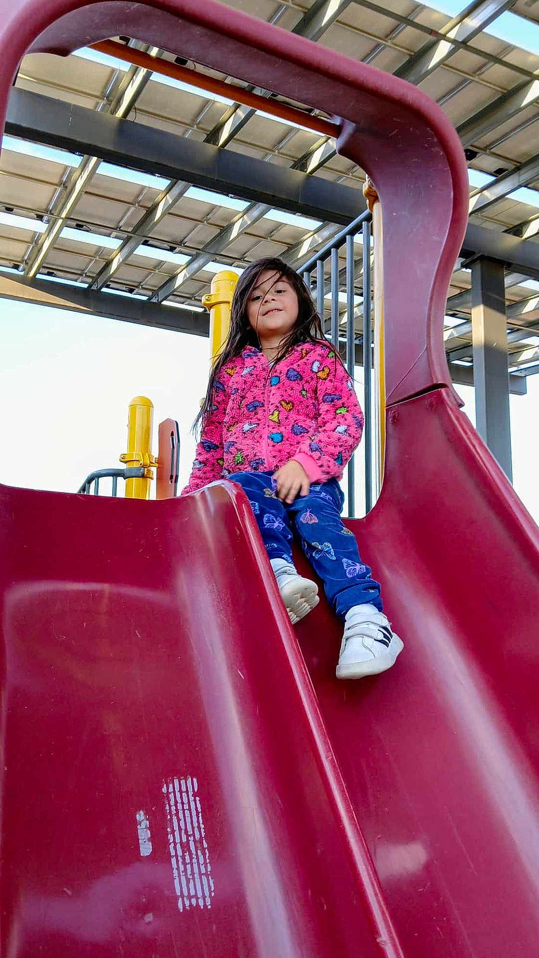 Aryah joined the competition — help win amazing prizes! child, slide, playground, outdoor, jacket, pants, shoes, play_equipment, smiling, happy, person, recreation, fun, daylight, structure, metal, plastic, clothing, activity, young