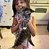 Aryah is registered to the contest to win money with this photo: animal, appliance, cat, child, curly_hair, cute, floor, furniture, holding, home, indoor, kitchen, magnet, pajamas, person, pet, refrigerator, stove, tile_floor, white_paws