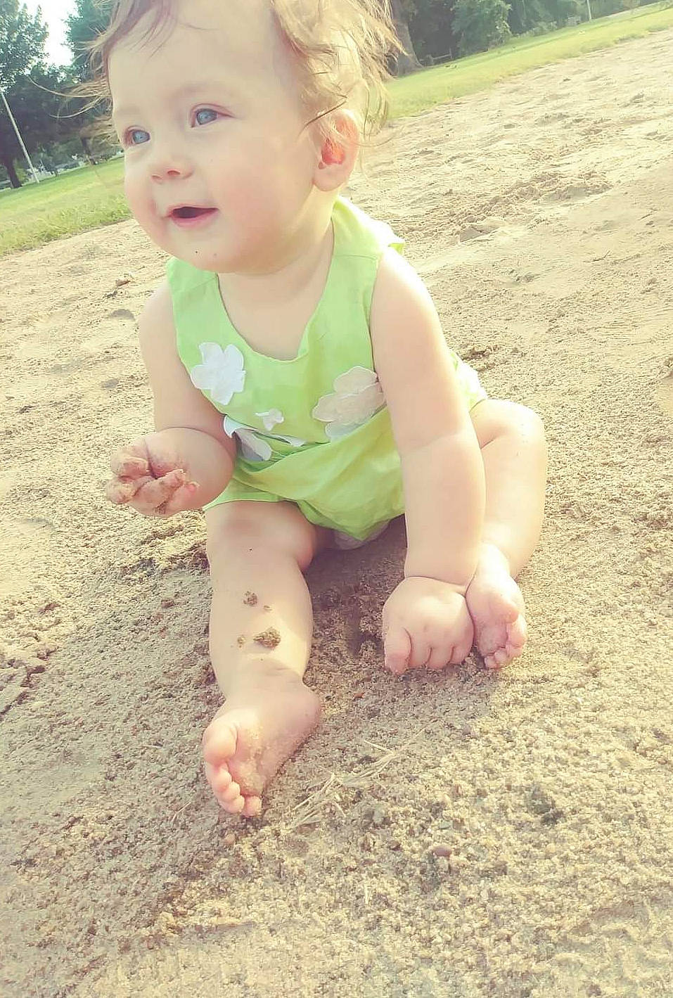 Kinsley is registered to the contest to win money with this photo: baby, baby_toddler_clothing, barefoot, child, eye, face, facial_expression, finger, gesture, grass, hand, happy, head, people_in_nature, person, sand, skin, smile, summer, thumb