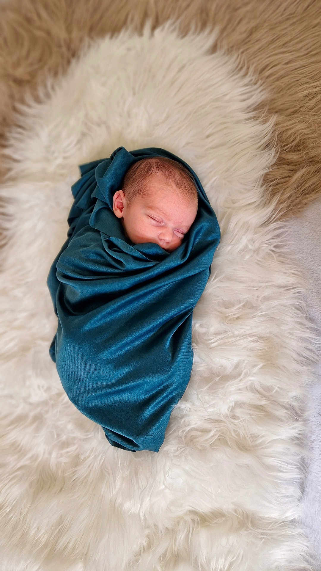 Lily-Rose participe au concours pour gagner de l'argent avec cette photo : newborn, baby, sleeping, swaddled, blanket, blue, fur_rug, soft_texture, peaceful, infant, portrait, cozy, cute, resting, wrapped, head, face, skin, closeup, indoors