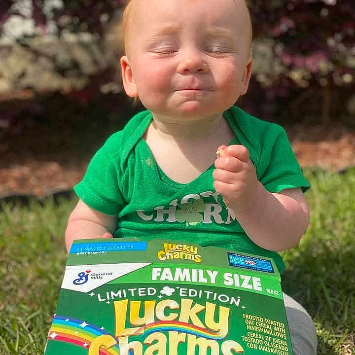 Charlie joined the competition — help win amazing prizes! baby, cereal_box, child, face, family_size, food, grass, green_shirt, happy, holding, limited_edition, lucky_charms, marshmallows, nature, outdoor, person, portrait, sitting, snack, sunlight