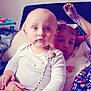Briec participe au concours pour gagner de l'argent avec cette photo : baby, child, sibling, indoor, toy, blue_eyes, curly_hair, white_clothing, pout, hand, colorful, playful, seated, pacifier_clip, blanket, couch, person, cute, family, toddler