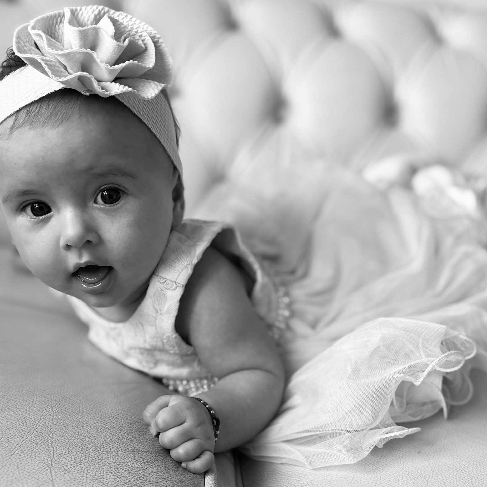 Ariana-Emilija joined the competition — help win amazing prizes! baby, black_and_white, child, close_up, couch, curious, cute, dress, flower, girl, headband, indoors, infant, leather, person, portrait, smiling, soft_focus, toddler, tulle