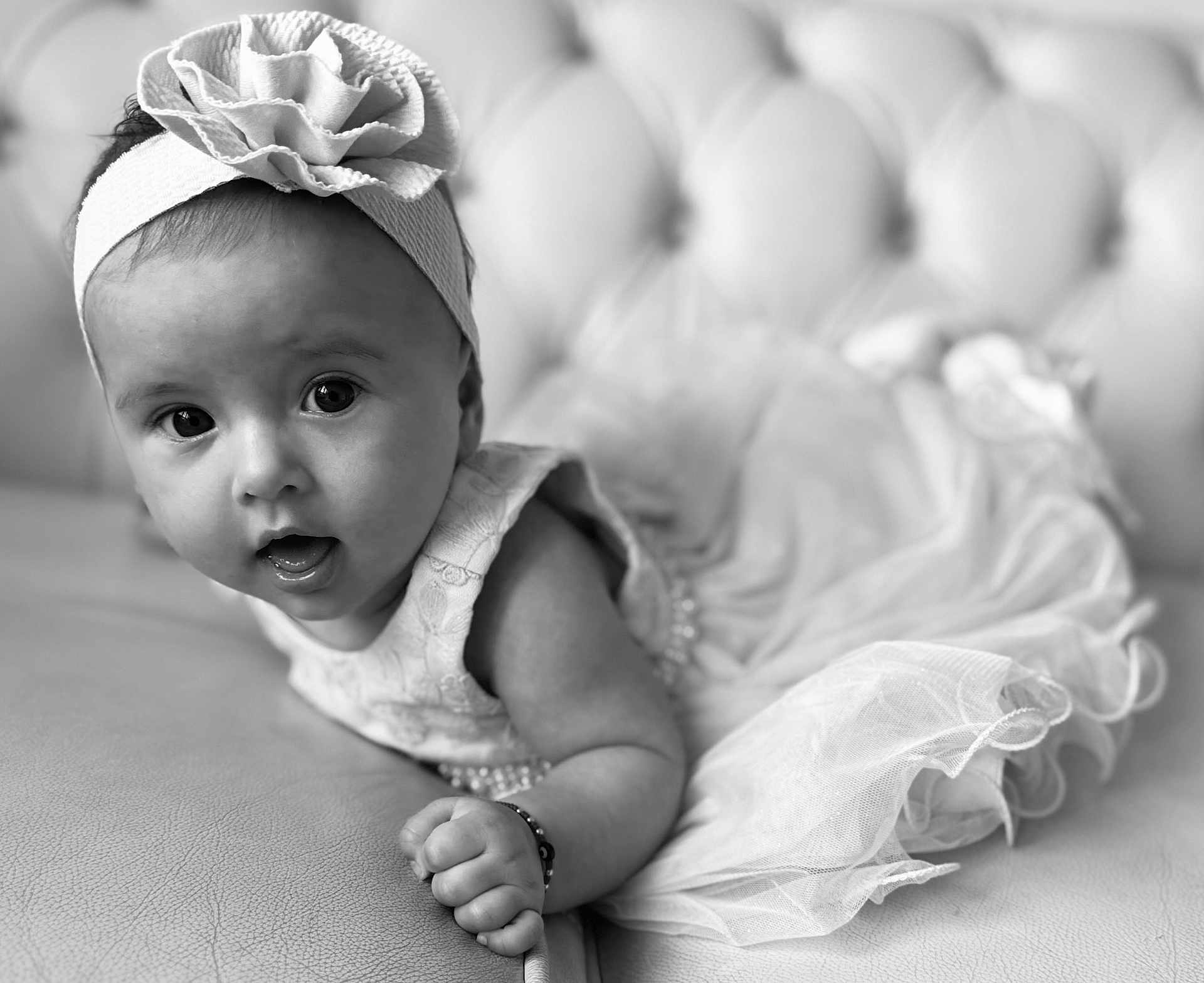 Ariana-Emilija joined the competition — help win amazing prizes! baby, infant, girl, headband, flower, dress, tulle, couch, leather, portrait, black_and_white, cute, curious, soft_focus, child, indoors, close_up, smiling, person, toddler