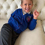 Danielius-aleksandras is registered to the contest to win money with this photo: child, boy, smile, blue_cardigan, dark_pants, sofa, leather_sofa, tufted_sofa, indoor, casual, happy, portrait, young_child, person, seated, relaxed, clothing, furniture, home, comfortable