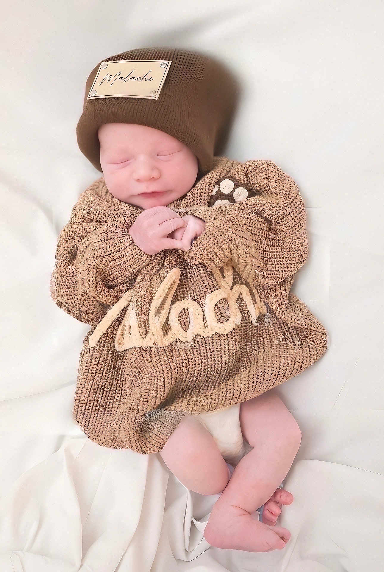 Malachi is registered to the contest to win money with this photo: newborn, baby, sleeping, knitted_sweater, hat, brown, cozy, blanket, soft, peaceful, cute, infant, resting, hands, legs, portrait, indoors, child, warm, toddler