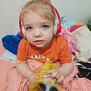 Sylas joined the competition — help win amazing prizes! toddler, child, headphones, orange_shirt, plush_toy, cat_toy, blue_eyes, indoor, blankets, colorful, soft, curly_hair, person, portrait, cute, young_child, seated, looking_at_camera, toy, cozy