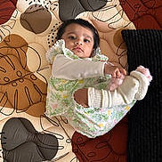 Vihaana is registered to the contest to win money with this photo: baby, blanket, child, colorful, comfort, cozy, curious, cute, floral_clothing, indoor, infant, lying_down, patterned, person, playful, portrait, quilt, socks, soft_toys, textile