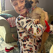 Shiny is registered to the contest to win money with this photo: child, dog, pajamas, mario_kart, smiling, indoor, living_room, couch, toy, carpet, collar, bow_tie, happy, pet, boy, cute, home, casual, playful, holding