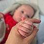 adult, baby, blurred_background, bond, child, closeup, finger, hand, holding, human, infant, intimacy, love, newborn, nursery, parent, red_clothing, skin, soft_focus, touch