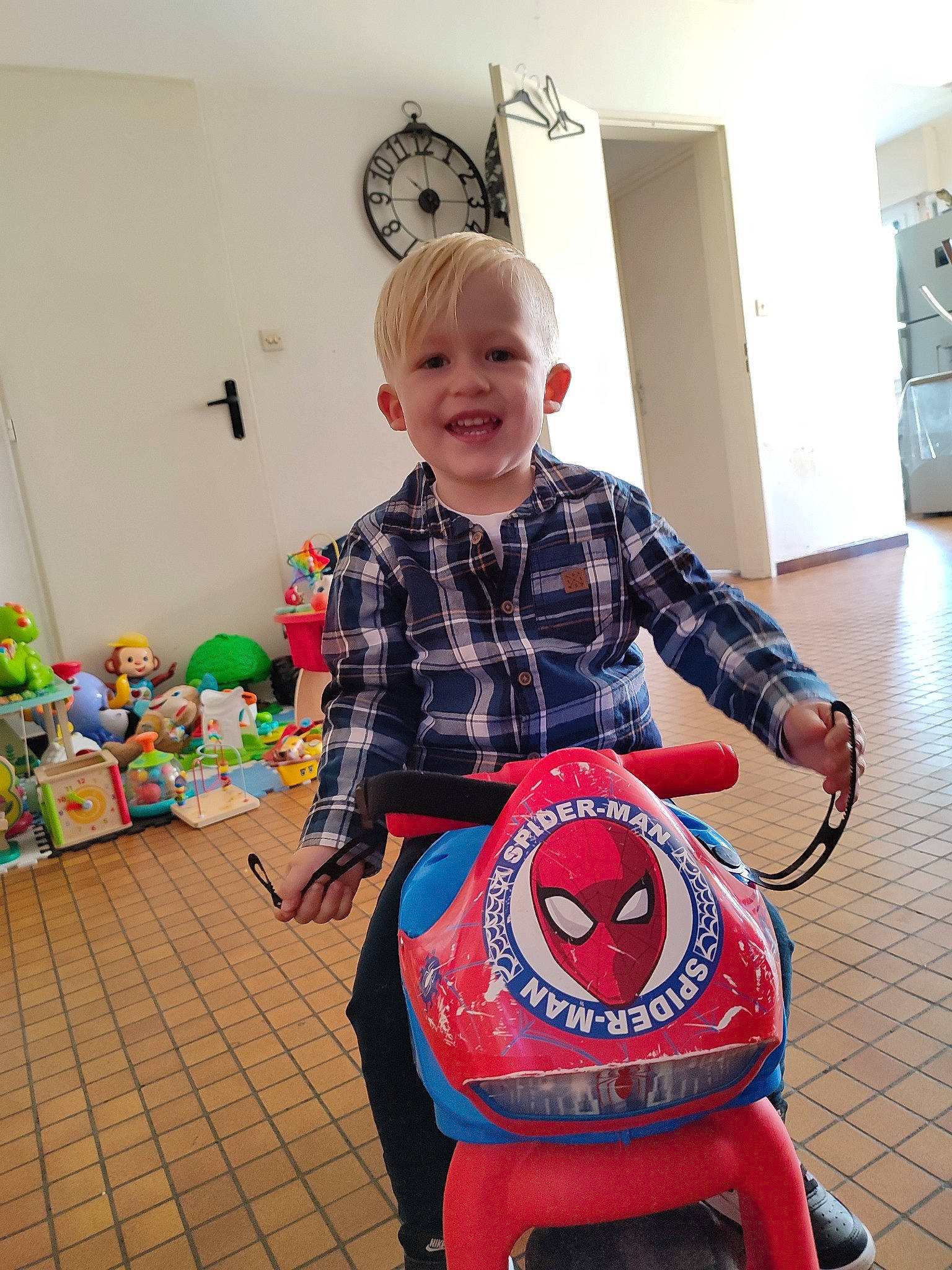 Sloan a rejoint le concours — aidez-le/la à gagner de superbes lots ! automotive_tire, clock, electric_blue, event, fender, floor, flooring, fun, joy, motor_vehicle, pattern, person, plaid, riding_toy, shoe, smile, standing, tartan, tire, toddler